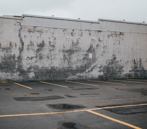 A parking lot with pot holes, needing improvements.